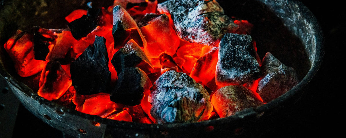 Como acender um kamado: pedaços de carvão vegetal em brasa num cesto redondo para carvão