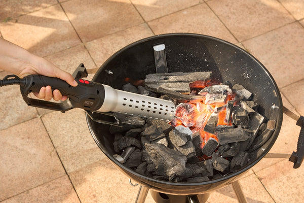 Isqueiro a pôr o carvão incandescente num churrasco esférico